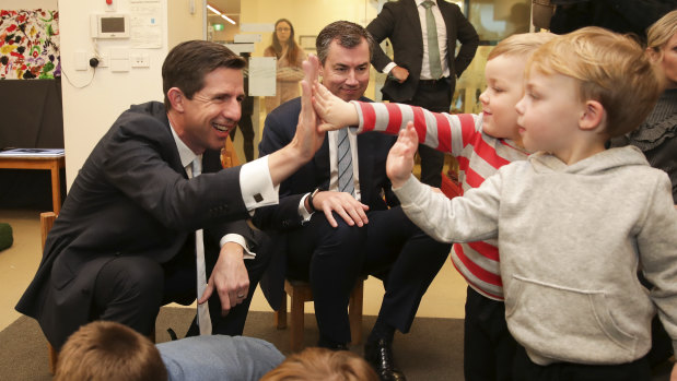 Minister for Education and Training Simon Birmingham and Minister for Human Services Michael Keenan high five children during a visit to the Acacia Child Care Centre. 