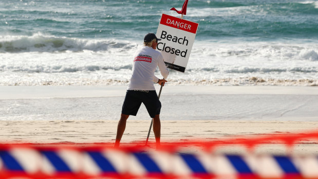 A Gold Coast lifeguard erects the beach closed sign. (File image)