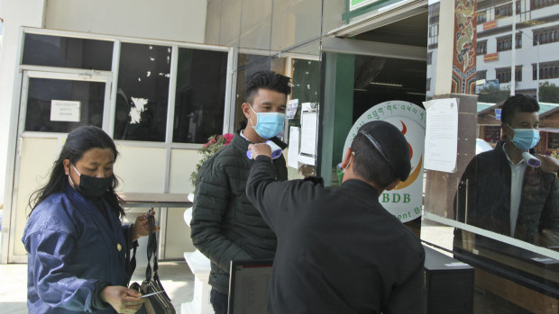 A security official takes the temperature of people as a precaution against the coronavirus in  the capital Thimpu.