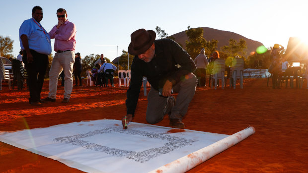 Noel Pearson signs a canvas on which the Uluru Statement from the Heart was later painted.