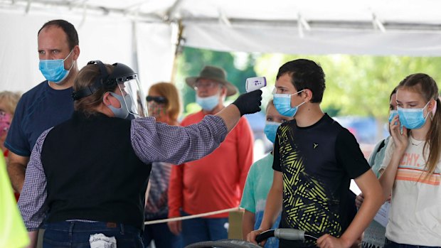 A Silver Dollar City employee takes the temperature of guests before they are allowed to enter the park near resort town of Branson, Missouri where authorities struggled to beat back a surge blamed on the fast-spreading Delta variant.