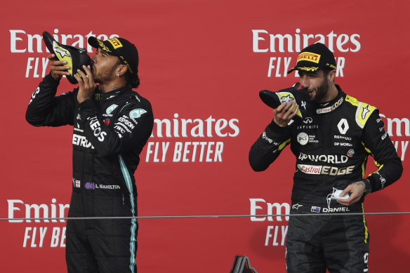 Daniel Ricciardo and Lewis Hamilton celebrate with a shoey on the podium.
