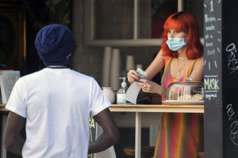 A woman wears a face mask as she gives a customer change at a cafe in Montreal on Sunday.