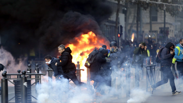 People run from a burning car during clashes with police on  Saturday in Marseille, southern France. 