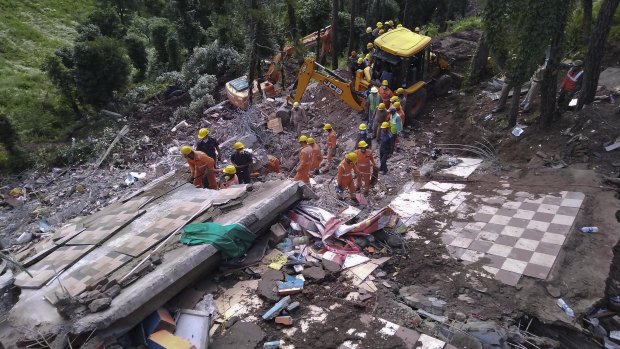 Rescuers look for survivors after a three-story building collapsed in monsoon rains near the town of Solan, India.