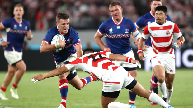 Vasily Dorofeev of Russia is tackled by Rikiya Matsuda of Japan.