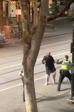 Police confront the alleged attacker on Bourke Street.