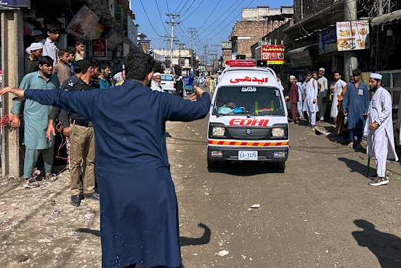 A volunteer clears the way for an ambulance transporting injured children.