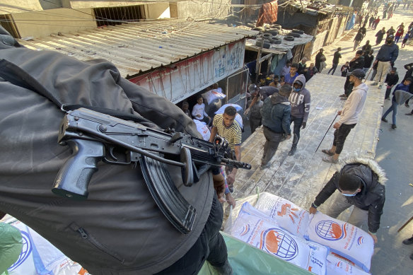 Palestinians unload wheat sacks from a humanitarian aid truck into a grocery store under guard by Hamas fighters in Rafah on Tuesday.