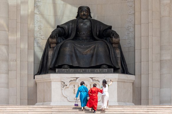 Mongolian women walk up to a statue of Genghis Khan in Ulaanbaatar’s main square. 