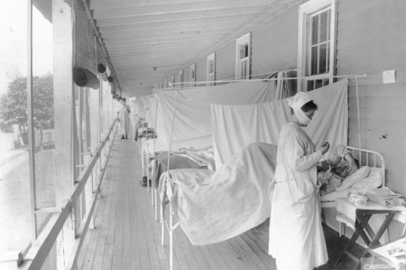 November 1918: a  a nurse takes the pulse of a patient in the influenza ward of the Walter Reed hospital in Washington. 