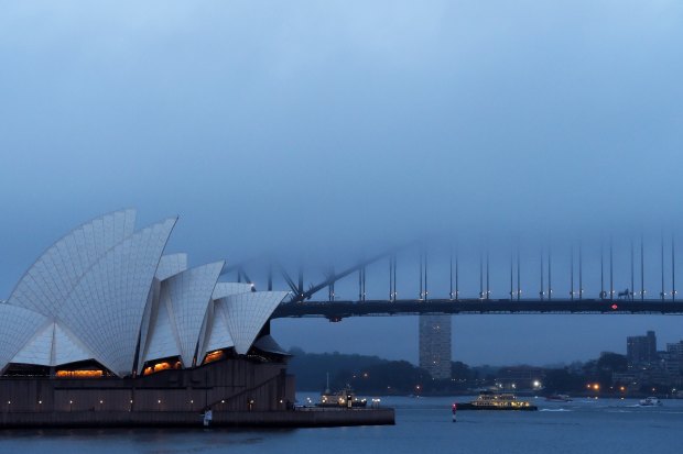 Fog and rain hang over the Opera House and Harbour Bridge.