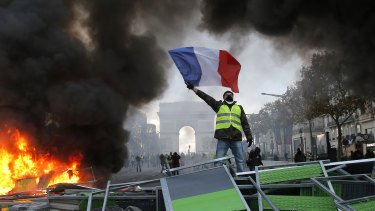 A demonstrator waves the French flag on a burning barricade on the Champs-Elysees with the Arc de Triomphe in the background, during a demonstration against the rise of fuel taxes. 
