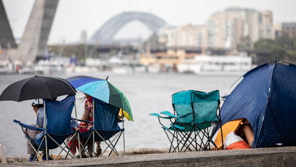 New Year's Eve revellers gather under shelter during the afternoon storm at Glebe Foreshore.