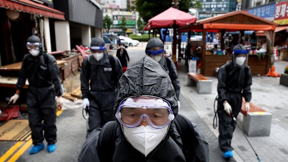 Health officials from Incheon, South Korea, wear spray anti-septic solution in an alley of markets and shopping district.