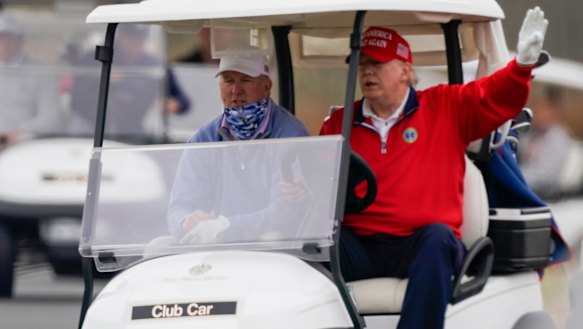 President Donald Trump drives a golf cart as he plays golf at Trump National Golf Club.