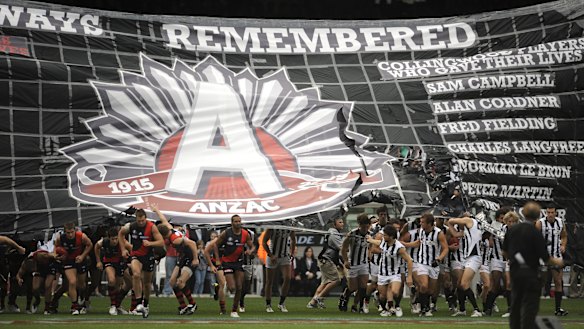 Both sides running through the ANZAC banner before the game.