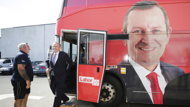 Opposition Leader Bill Shorten exits the campaign bus featuring the face of WA Premier Mark McGowan during his visit to the Volgren bus facility in Perth on Wednesday.