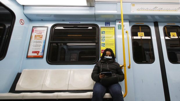 A woman wearing a face mask checks her phone in a subway carriage in Milan, Italy.