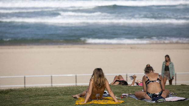 People sit beside a closed Bondi Beach on Friday afternoon.