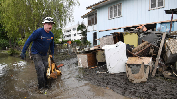 Chris Mitchell removes flood damaged items out of his father in-law's house in the Townsville suburb of Rosslea.