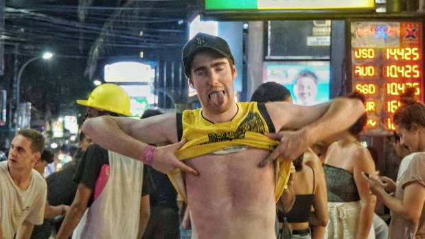 A schoolie pulls faces at the camera while walking along Legian street in Bali.