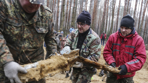 Three men carry a sand-covered part of a World War II B-25 Mitchell bomber used by the Soviet air force when it was downed in 1945 by a German fighter near the town of Bierun, southern Poland.