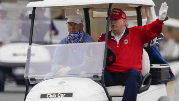 President Donald Trump drives a golf cart as he plays golf at Trump National Golf Club.