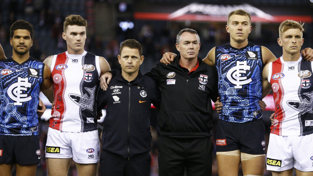 Blues head coach Brendon Bolton (centre left) and Saints head coach Alan Richardson (centre right) link arms with players before the Sir Doug Nicholls Round match at Marvel Stadium in Melbourne.