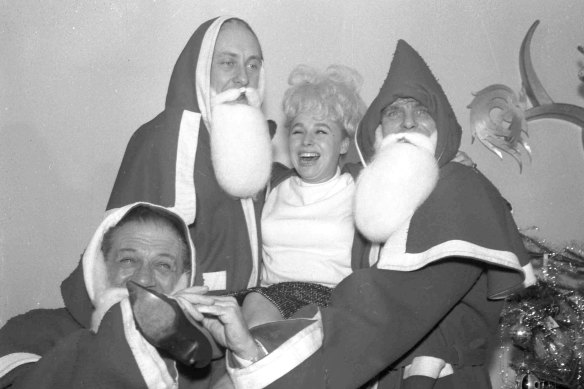 In this 1963 photo, British comedians Sid James, left, Hughie Green and Dickie Henderson, right, carry British actress Barbara Windsor during the Variety Club of Great Britain Christmas luncheon at the Savoy Hotel in London.