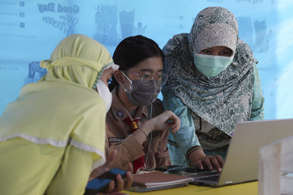 A mother, right, and her daughter, centre, use free Wi-Fi to access an online lesson inside a temporary tent in Jakarta, Indonesia.