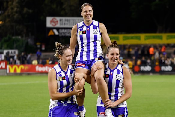Jasmine Garner of the Kangaroos is chaired from the field after her 100th match by teammates Kim Rennie (left) and Emma King (right).