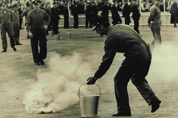 Policeman moves in to remove a smoke bomb.