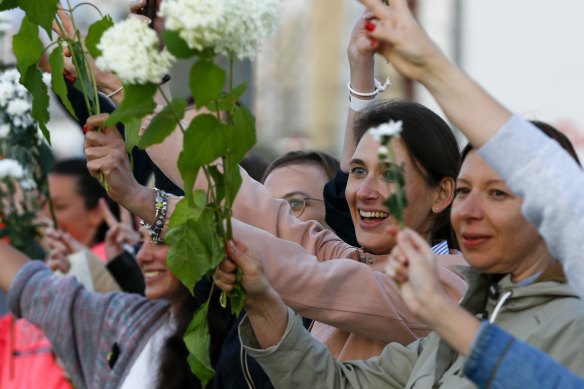 Women wave flowers as they join the fifth day of protests against Sunday's election results.