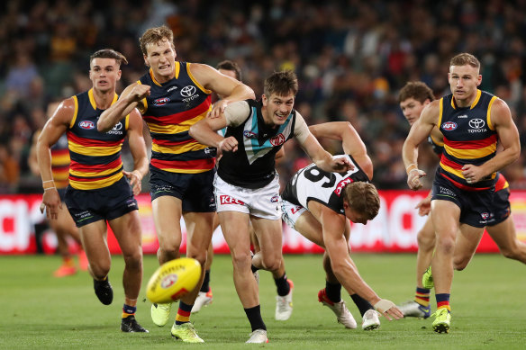 Jordan Dawson of the Crows and Zak Butters of the Power chase the footy.