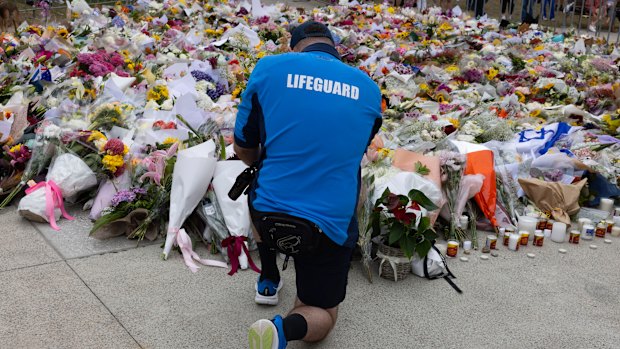 A lifeguard places flowers at the  memorial for the mass-shooting victims at the Bondi Pavilion.