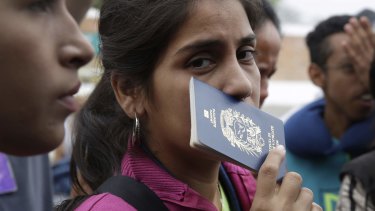 A Venezuelan migrant holds her passport while wait in line to take a bus to continue their travel in Tumbes, Peru.