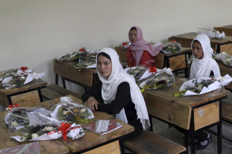 Schoolgirls sit inside a classroom with bouquets of flowers on empty desks as a tribute to those killed in the brutal May 8 bombing of the Syed Al-Shahda girls school, in Kabul, Afghanistan, Sunday, May 16, 2021.