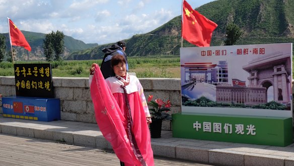 A Chinese tourist puts on a traditional Korean costume to take pictures on the riverfront promenade in Tumen, China.