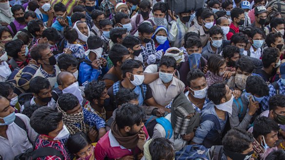 Indian migrant workers crowd to board buses to return to their native villages after a nationwide lockdown was announced.