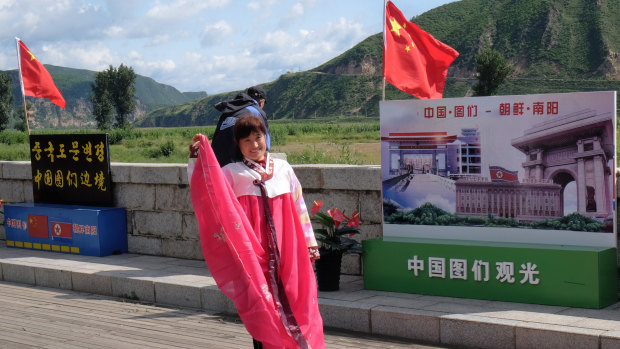 A Chinese tourist puts on a traditional Korean costume to take pictures on the riverfront promenade in Tumen, China.