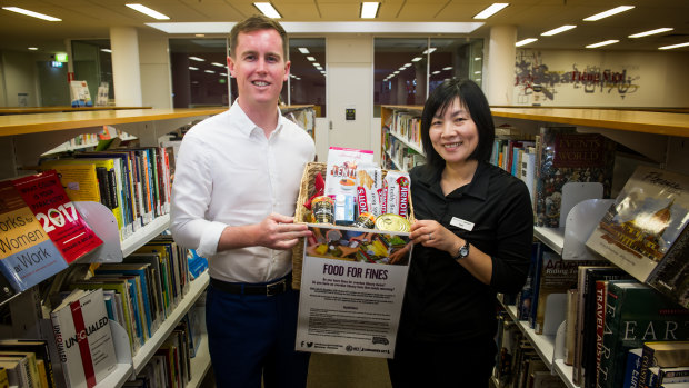 City Services Minister Chris Steel with l library service officer, Yumi Ezaki, at Civic Library to launch the Food for Fines program.