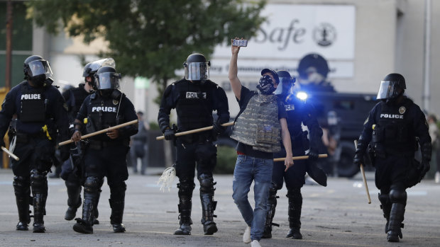 A protester walks in front of police at a demonstration in Louisville over the deaths of George Floyd and Breonna Taylor. Taylor, a black woman, was fatally shot by police in her home in March.