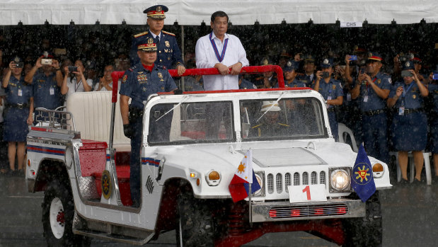 President Rodrigo Duterte, right, reviews a police  gathering under a sudden downpour last week.