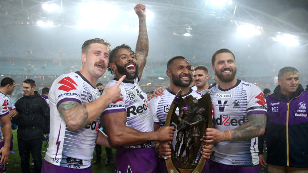 Justin Olam with Storm teammates and the premiership trophy in 2020.