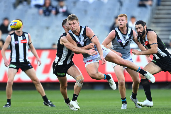 Port’s Ollie Wines handballs as he is tackled by Taylor Adams.