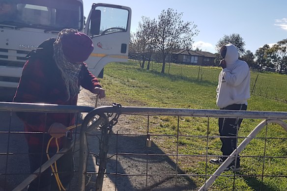 Two tip truck operators stand at the gate of Suji An’s Diggers Rest property, which was being used as an illegal tip.