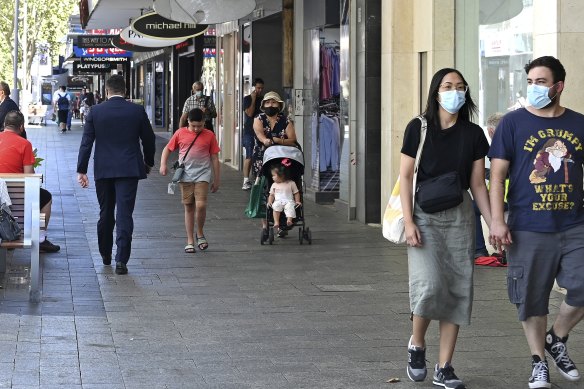 Shoppers walk through Hay Street Mall, some in masks and others not, on January 27.