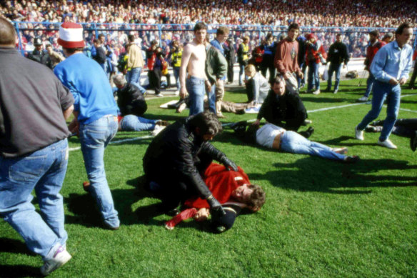 Stewards and supporters tend and care for wounded supporters on the field at Hillsborough Stadium in 1989.