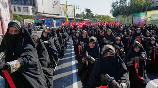 Women affiliated with Iran’s Revolutionary Guard carry rifles as they stand during the state-organised “Janfada” or “Sacrifice for Iran”.